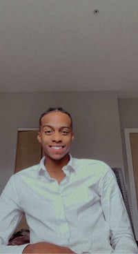 a man in a white shirt smiling in front of a camera